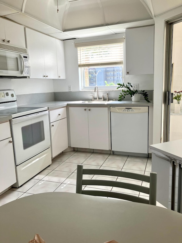 3590 Via Poinciana Unit 303, Lake Worth, FL 33467 - kitchen featuring white appliances, light countertops, white cabinets, and light tile patterned floors