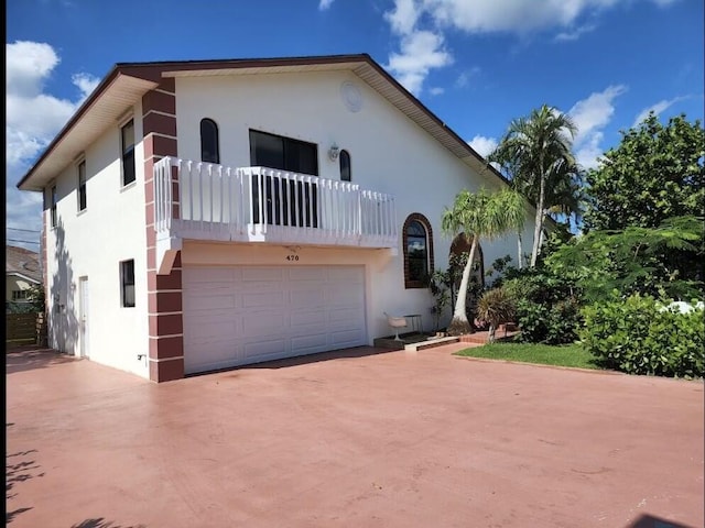 470 S Mars Way NE, Juno Beach, FL 33408 - view of front of home featuring a balcony, a garage, stucco siding, and concrete driveway