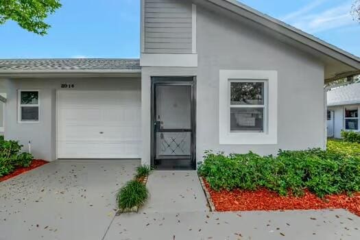8914 Windtree St, Boca Raton, FL 33496 - view of front of property featuring stucco siding, an attached garage, and driveway
