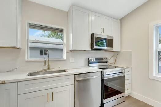 8914 Windtree St, Boca Raton, FL 33496 - kitchen featuring appliances with stainless steel finishes, a sink, white cabinets, light countertops, and baseboards