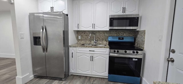 1510 S 23rd Ave, Hollywood, FL 33020 - kitchen with stainless steel appliances, a sink, wood finished floors, white cabinets, and tasteful backsplash