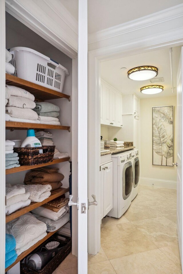 5050 N Ocean Dr Unit 701, Singer Island, FL 33404 - washroom with cabinet space, independent washer and dryer, baseboards, light tile patterned floors, and ornamental molding
