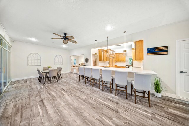7903 Plantation Lakes Dr NW, Port Saint Lucie, FL 34986 - kitchen with light wood-type flooring, a breakfast bar area, baseboards, a peninsula, and recessed lighting