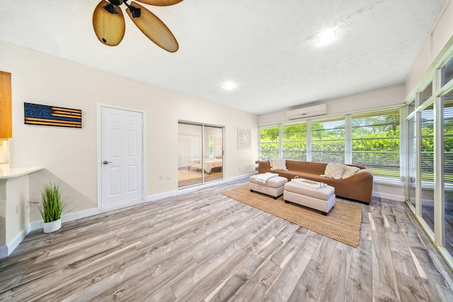 7903 Plantation Lakes Dr NW, Port Saint Lucie, FL 34986 - living room with an AC wall unit, ceiling fan, wood finished floors, baseboards, and a textured ceiling