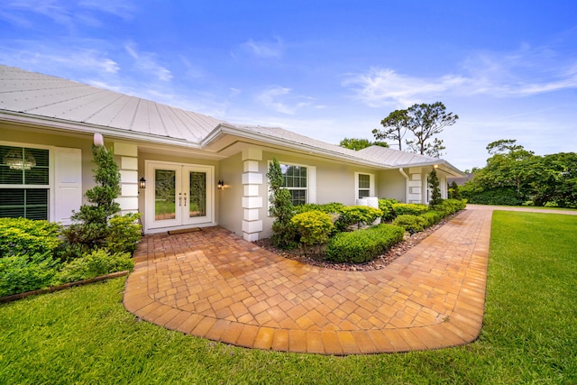 7903 Plantation Lakes Dr NW, Port Saint Lucie, FL 34986 - view of exterior entry with french doors, a yard, and stucco siding