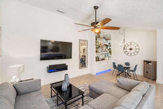 9132 Sun Terrace Cir Unit D, Palm Beach Gardens, FL 33403 - living room with wood finished floors, a ceiling fan, a chandelier, baseboards, and a textured ceiling