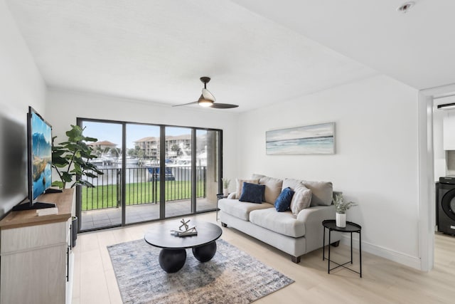 1601 Marina Isle Way Unit 101, Jupiter, FL 33477 - living area featuring light wood-type flooring, washer / dryer, a ceiling fan, and baseboards