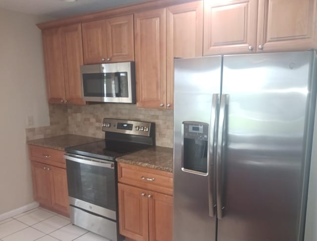 8205 Winnipesaukee Way, Lake Worth, FL 33467 - kitchen featuring appliances with stainless steel finishes, decorative backsplash, light tile patterned floors, dark stone counters, and brown cabinets
