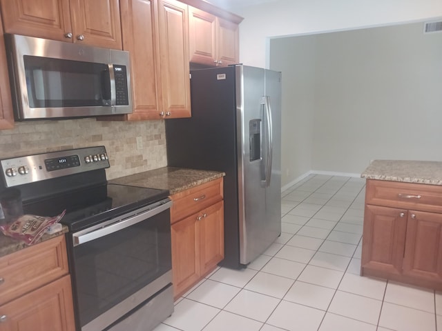 8205 Winnipesaukee Way, Lake Worth, FL 33467 - kitchen featuring stainless steel appliances, backsplash, light tile patterned flooring, dark stone countertops, and brown cabinetry