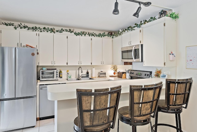 506 5th Ter, Palm Beach Gardens, FL 33418 - kitchen with stainless steel appliances, a sink, light countertops, a kitchen breakfast bar, and white cabinets