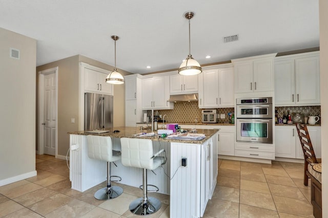 101 Saint Pierre Way, Jupiter, FL 33458 - kitchen with stainless steel appliances, decorative backsplash, white cabinetry, stone counters, and under cabinet range hood