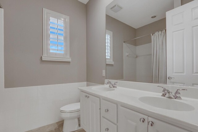 101 Saint Pierre Way, Jupiter, FL 33458 - full bath with toilet, double vanity, curtained shower, tile walls, and wainscoting