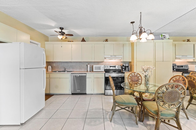 221 SE 9th Ave Unit 202, Pompano Beach, FL 33060 - kitchen featuring stainless steel appliances, under cabinet range hood, backsplash, a sink, and a textured ceiling