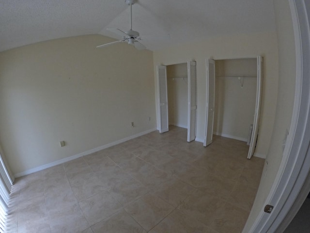1713 Mariners Cv Unit 7C, Fort Pierce, FL 34950 - unfurnished bedroom featuring two closets, vaulted ceiling, a ceiling fan, and light tile patterned flooring