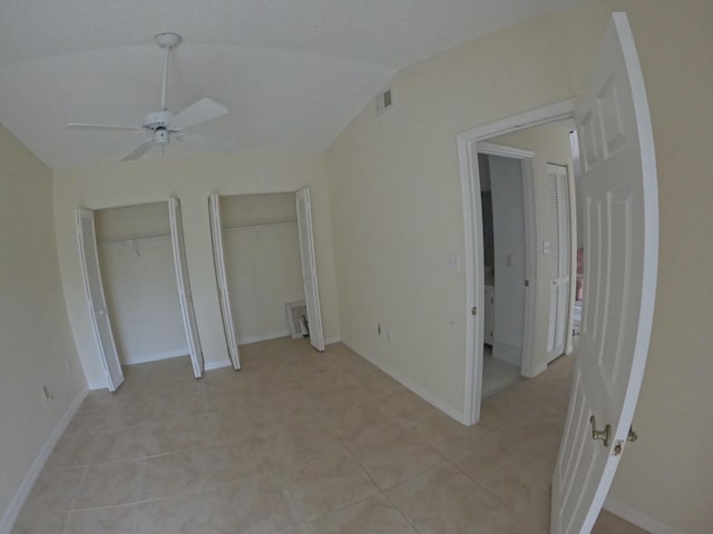 1713 Mariners Cv Unit 7C, Fort Pierce, FL 34950 - unfurnished bedroom featuring two closets, light tile patterned floors, baseboards, lofted ceiling, and a ceiling fan