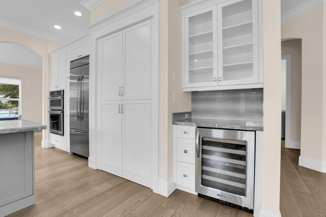 6688 Duckweed Rd, Lake Worth, FL 33449 - kitchen with wine cooler, arched walkways, stainless steel appliances, light wood-style floors, and light stone countertops