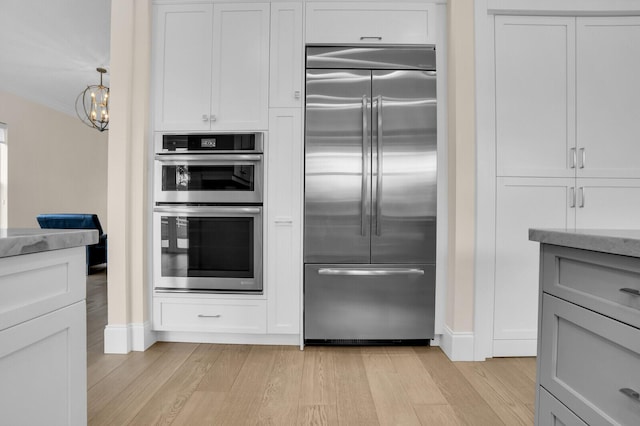 6688 Duckweed Rd, Lake Worth, FL 33449 - kitchen with appliances with stainless steel finishes, light wood-style floors, light stone countertops, a chandelier, and baseboards