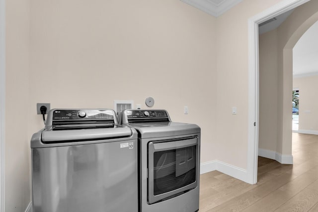 6688 Duckweed Rd, Lake Worth, FL 33449 - washroom featuring washer and clothes dryer, arched walkways, ornamental molding, light wood-type flooring, and baseboards