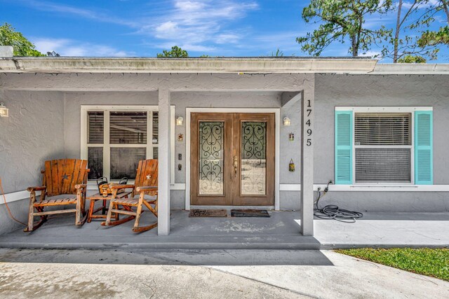 17495 40th Run N, Loxahatchee, FL 33470 - doorway to property featuring stucco siding and a porch