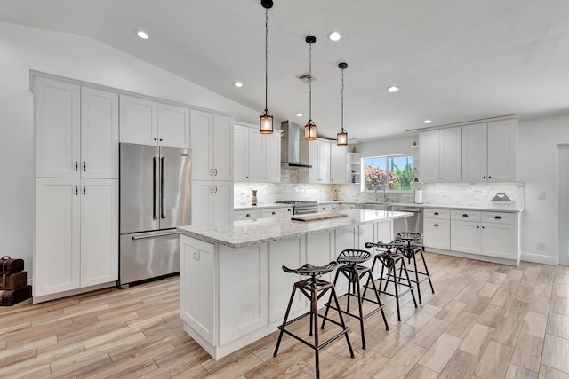 17495 40th Run N, Loxahatchee, FL 33470 - kitchen with high end appliances, wall chimney range hood, a sink, light wood finished floors, and a center island