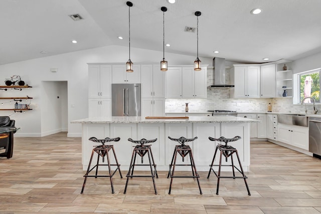 17495 40th Run N, Loxahatchee, FL 33470 - kitchen featuring appliances with stainless steel finishes, wall chimney exhaust hood, a sink, open shelves, and vaulted ceiling