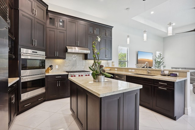 16770 Burlington Bristol Ln, Delray Beach, FL 33446 - kitchen with appliances with stainless steel finishes, under cabinet range hood, a peninsula, a sink, and light marble finish flooring