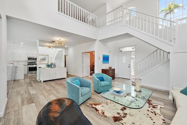 8208 Heritage Club Dr, West Palm Beach, FL 33412 - living area with a towering ceiling, stairs, light wood-type flooring, a chandelier, and baseboards