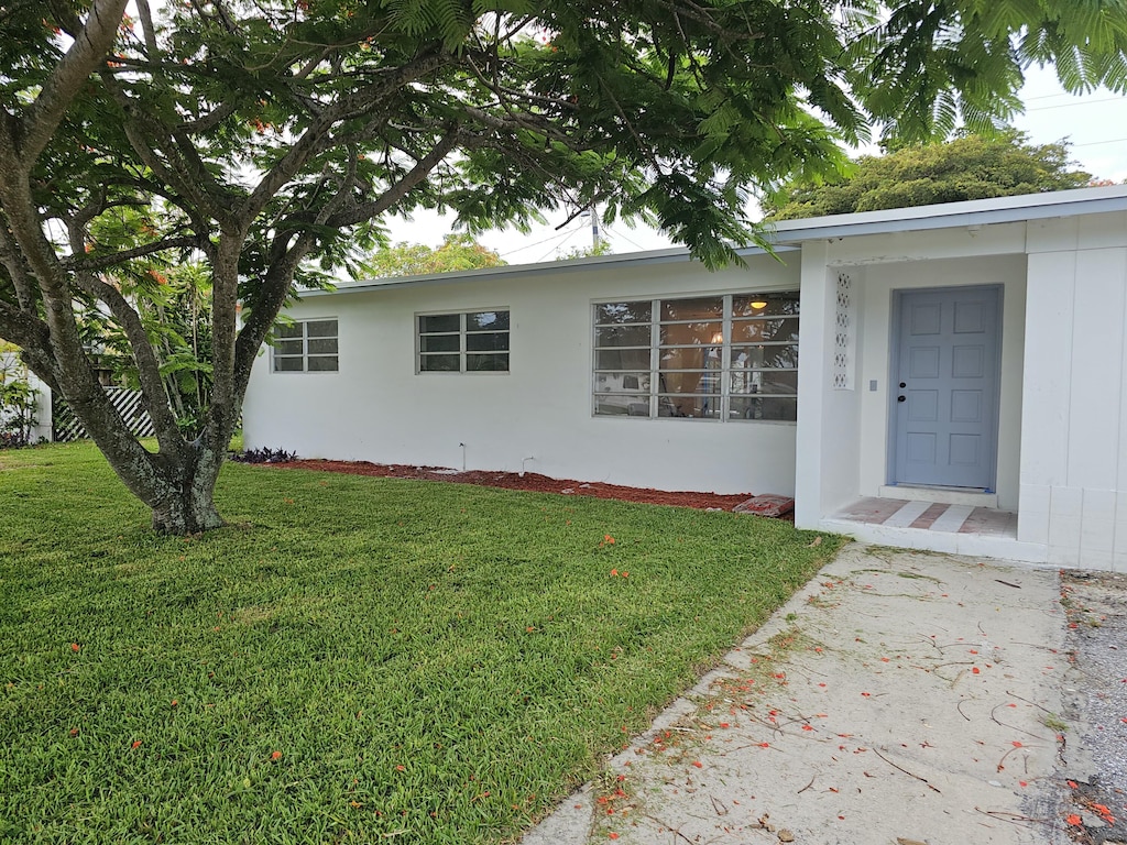 99 Henthorne Dr, Palm Springs, FL 33461 - view of exterior entry featuring a lawn and stucco siding