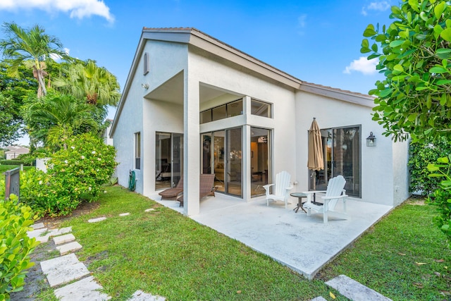 10194 N Lexington Cir, Boynton Beach, FL 33436 - back of property with stucco siding, a patio, and a lawn