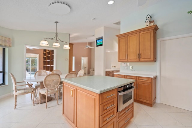4402 SW Dundee Ct, Palm City, FL 34990 - kitchen with oven, light tile patterned floors, light countertops, a ceiling fan, and a kitchen island