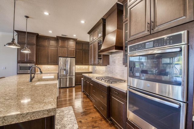 4858 Marginada Way, Lake Worth, FL 33467 - kitchen featuring stainless steel appliances, premium range hood, dark brown cabinets, dark wood finished floors, and decorative backsplash