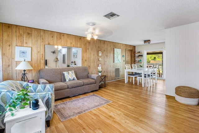 4971 N Kay St, Palm Beach Gardens, FL 33418 - living room with light wood-type flooring, wood walls, a ceiling fan, and a textured ceiling