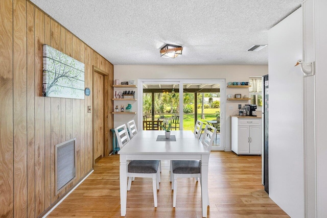 4971 N Kay St, Palm Beach Gardens, FL 33418 - dining area with wooden walls, light wood-style floors, and a textured ceiling