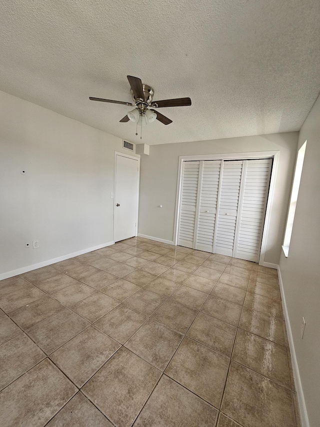 2800 NW 56th Ave Unit C306, Lauderhill, FL 33313 - unfurnished bedroom with a textured ceiling, a closet, baseboards, ceiling fan, and tile patterned flooring