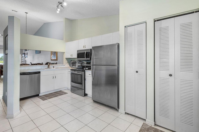 15318 W Tranquility Lake Dr, Delray Beach, FL 33446 - kitchen with appliances with stainless steel finishes, light countertops, white cabinets, lofted ceiling, and a textured ceiling