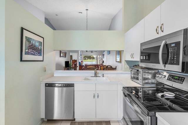 15318 W Tranquility Lake Dr, Delray Beach, FL 33446 - kitchen featuring appliances with stainless steel finishes, a sink, light countertops, lofted ceiling, and white cabinetry