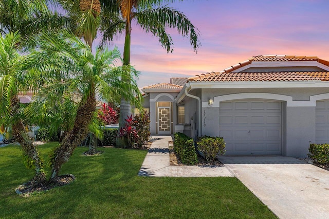 15318 W Tranquility Lake Dr, Delray Beach, FL 33446 - view of front of home featuring a tiled roof, an attached garage, stucco siding, concrete driveway, and a yard
