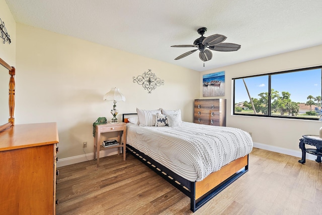 6860 SE Constitution Blvd Unit 204, Hobe Sound, FL 33455 - bedroom with baseboards, light wood-type flooring, a textured ceiling, and a ceiling fan