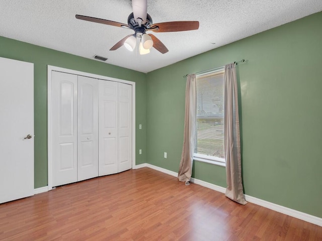 1030 Locust Ave NW, Palm Bay, FL 32907 - unfurnished bedroom with wood finished floors, a textured ceiling, a closet, baseboards, and a ceiling fan