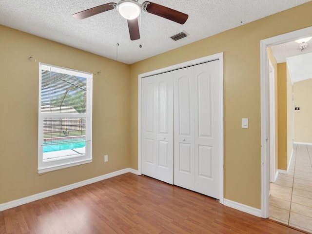 1030 Locust Ave NW, Palm Bay, FL 32907 - unfurnished bedroom with wood finished floors, a closet, baseboards, a textured ceiling, and a ceiling fan