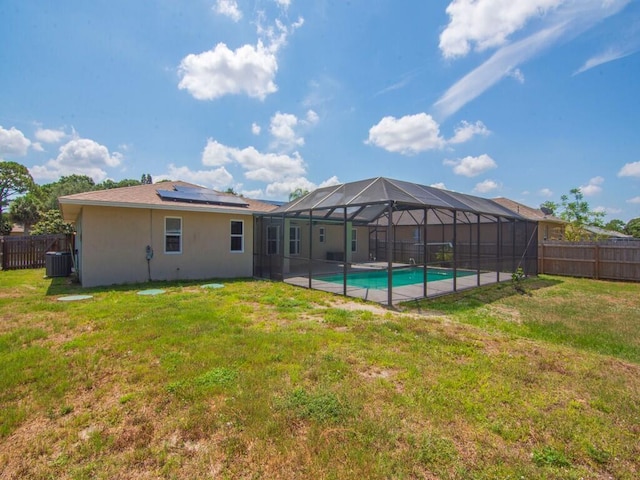 1030 Locust Ave NW, Palm Bay, FL 32907 - rear view of house featuring cooling unit, roof mounted solar panels, stucco siding, and glass enclosure