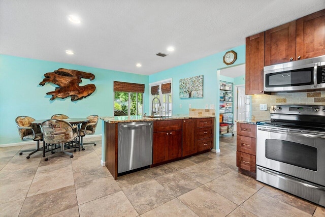 1858 Bartlett Ct, Lake Clarke Shores, FL 33406 - kitchen featuring stainless steel appliances, a sink, light stone countertops, decorative backsplash, and baseboards