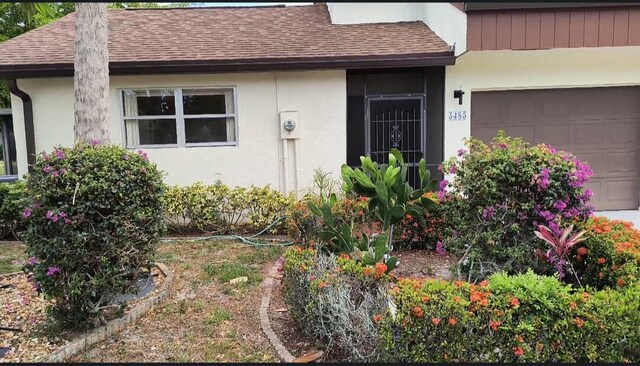 3485 Stanton Ter, Lake Worth, FL 33467 - view of exterior entry with roof with shingles, an attached garage, and stucco siding