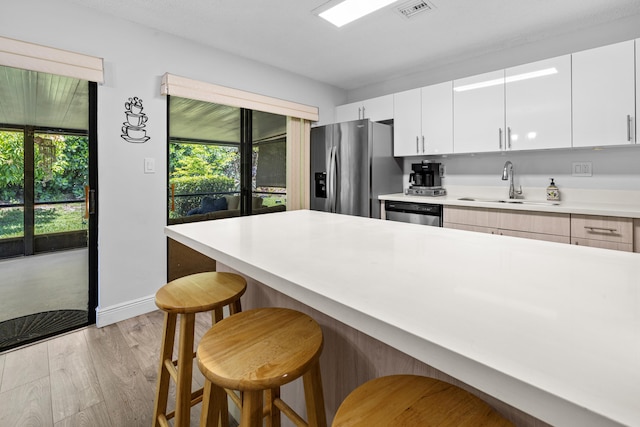 5135 Mirror Lakes Blvd, Boynton Beach, FL 33472 - kitchen with appliances with stainless steel finishes, a sink, a breakfast bar, light wood-style floors, and light countertops