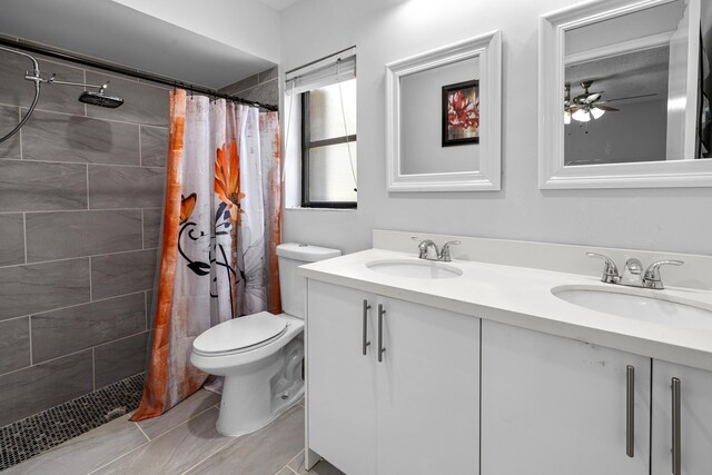 5135 Mirror Lakes Blvd, Boynton Beach, FL 33472 - bathroom featuring double vanity, toilet, tiled shower, ceiling fan, and tile patterned floors