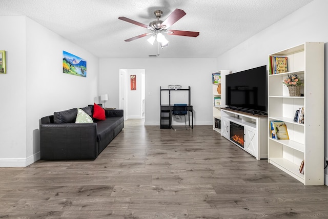 5135 Mirror Lakes Blvd, Boynton Beach, FL 33472 - living area featuring ceiling fan, wood finished floors, a glass covered fireplace, a textured ceiling, and baseboards
