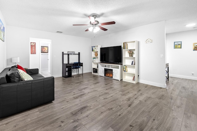 5135 Mirror Lakes Blvd, Boynton Beach, FL 33472 - living area featuring a ceiling fan, wood finished floors, a textured ceiling, a glass covered fireplace, and baseboards