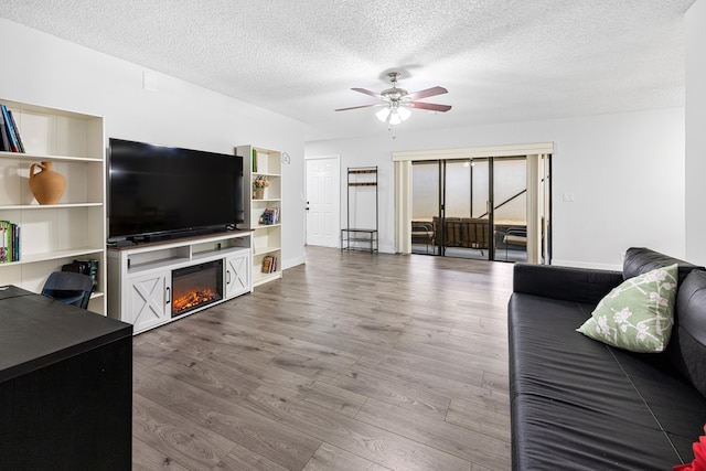 5135 Mirror Lakes Blvd, Boynton Beach, FL 33472 - living area with ceiling fan, a glass covered fireplace, wood finished floors, a textured ceiling, and baseboards