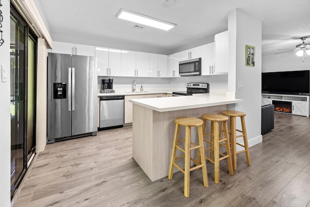 5135 Mirror Lakes Blvd, Boynton Beach, FL 33472 - kitchen with appliances with stainless steel finishes, a sink, a peninsula, light wood-type flooring, and ceiling fan