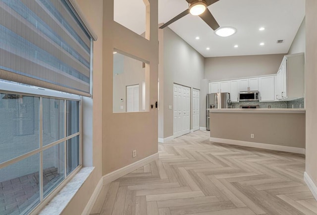 8592 Logia Cir, Boynton Beach, FL 33472 - kitchen with appliances with stainless steel finishes, a high ceiling, white cabinets, baseboards, and a ceiling fan